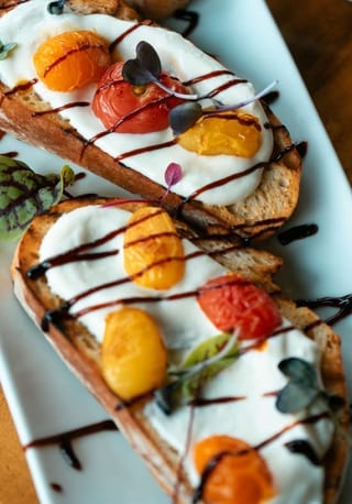Ricotta crostini topped with tomatoes and balsamic glaze