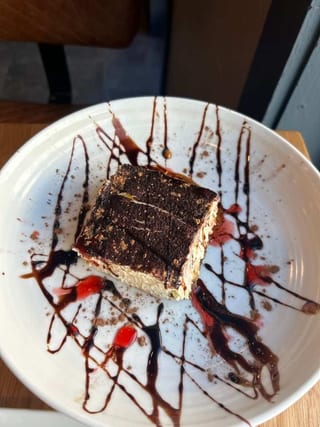 Tiramisu with chocolate drizzle on a white plate